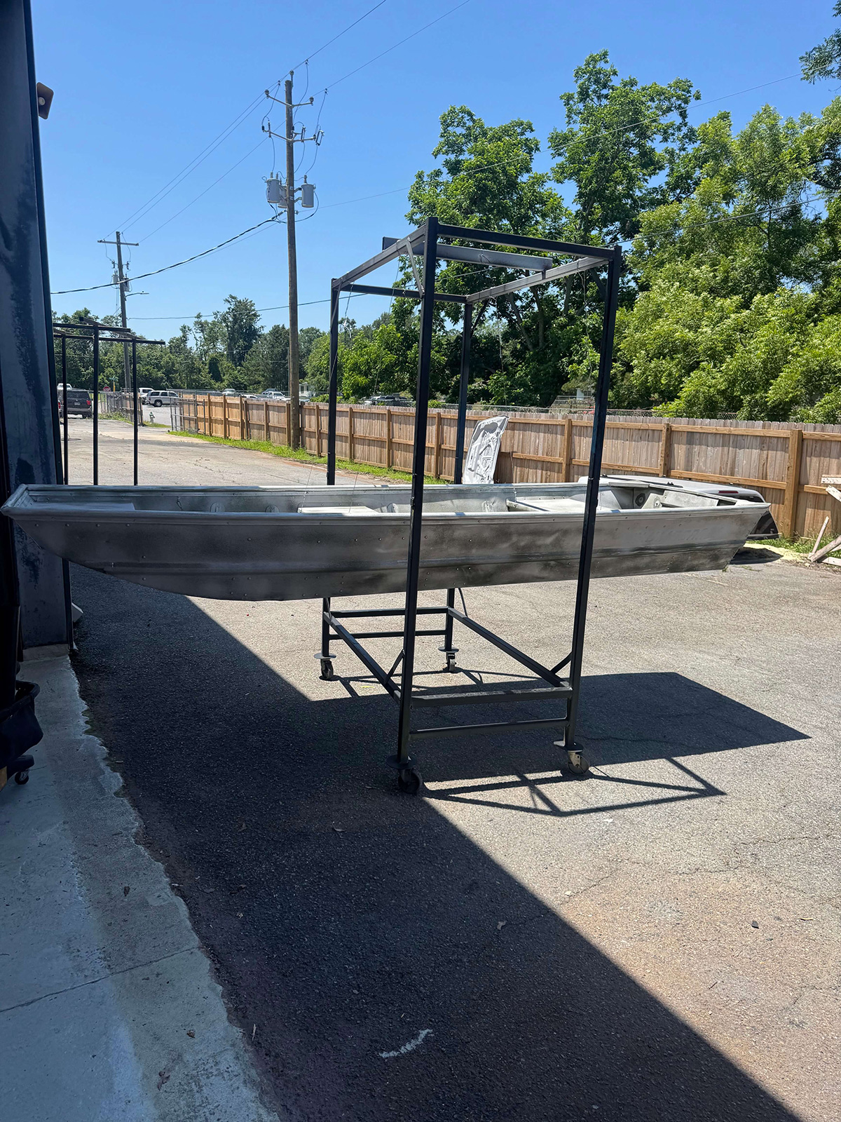 Full aluminum boat hull on a rolling rack outside the shop.