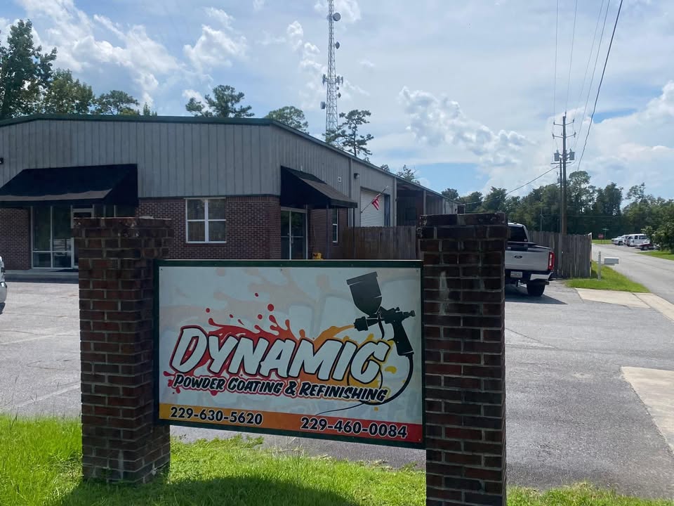 Shop road sign on brick pillars in front of the grey metal and brick building. DYNAMIC Powder Coating and Refinishing, 229-630-5620.